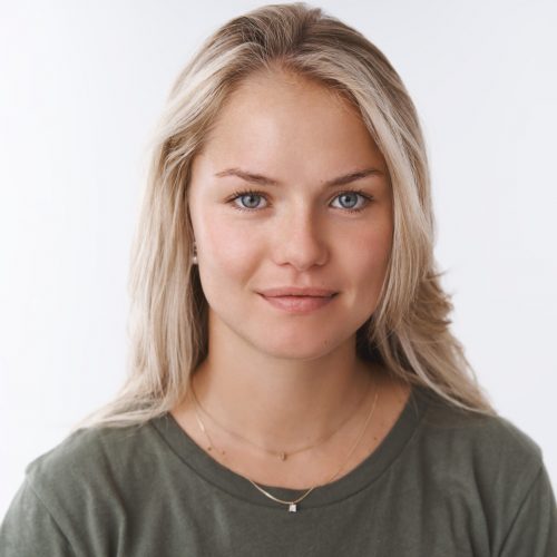 Young attractive adult woman with blond short hair tanned smiling cute and gazing at camera with friendly, pleasant attitude expressing caring and tender emotions against white background.